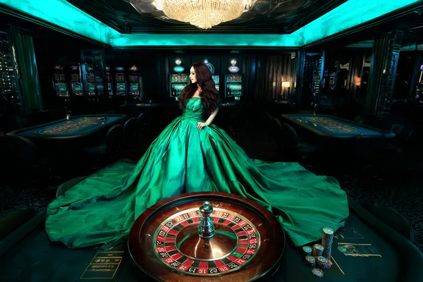 SOUL777BET — A high-class gaming experience without limits A woman in a luxurious green gown next to an ornate roulette wheel, capturing the upscale casino mood of SOUL777BET.